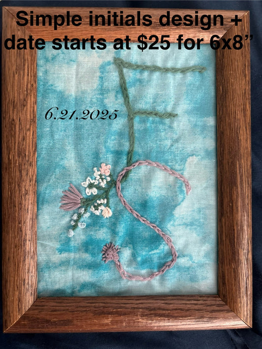 Embroidered design with initials and date on fabric in a wooden frame, priced at $25 for 6x8" simple initials and date design. Custom Framed Embroidery Design - Perfect Wedding Gift, Wedding Keepsake, Birth Announcement, Special Dates, shown is an embroidered F+S with a date, flowers, mountains, and other small details included on a blue cloud background inside a wooden frame